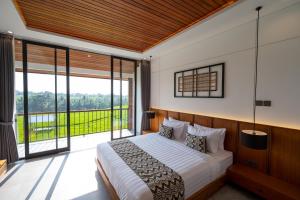 a bedroom with a large bed and a large window at Kairos Villa Ubud by Omkara Experience in Ubud