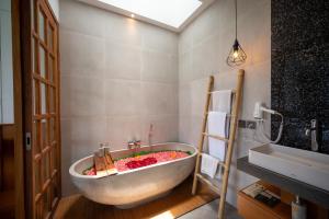 a bathroom with a large tub with flowers in it at Kairos Villa Ubud by Omkara Experience in Ubud