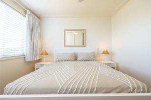 a white bedroom with a large bed with two lamps at 23 Lentara St - pet friendly, air con, Wi-Fi, boat parking in Fingal Bay +31 photos