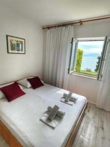 Schlafzimmer mit einem großen weißen Bett und einem Fenster in der Unterkunft Apartments Sea View - cosy & comfortable in Brist