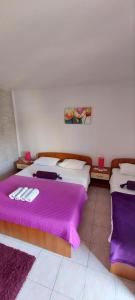 a bedroom with two beds with purple sheets at Apartments Ivana - free parking and 100m from the beach in Trpanj