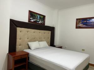 a bedroom with two white beds and two pictures on the wall at Hotel King David Ecuador in Nueva Loja