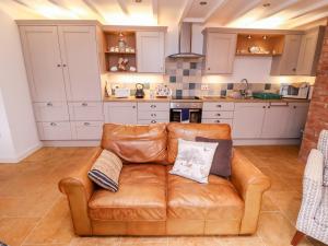 Askham的住宿－The Granary，客厅设有厨房,配有棕色真皮沙发