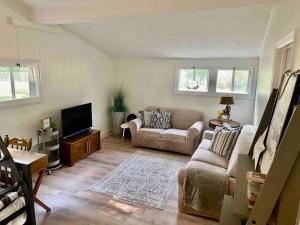 ein Wohnzimmer mit einem Sofa und einem TV in der Unterkunft Cozy Neutral Farmhouse, Coffee provided, Relaxation optional in Muskegon