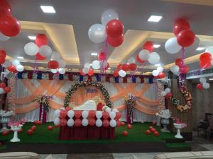 un salón de banquetes de cumpleaños con globos rojos y blancos y un escenario en The Metropol Hotel Siwan en Siwān