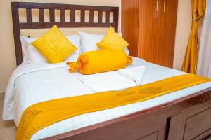 a bed with yellow and white sheets and yellow pillows at Cozy apartment kisii in Kisii