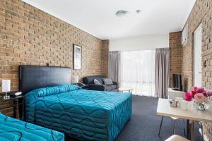 a hotel room with a bed and a brick wall at Marion Motel and Apartments in Adelaide