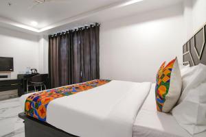 een wit bed in een kamer met een bureau bij FabHotel Greysky in New Delhi