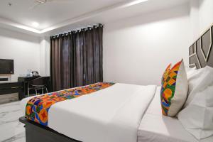 a white bed in a room with a desk at FabHotel Sky Suites Karkardooma in New Delhi
