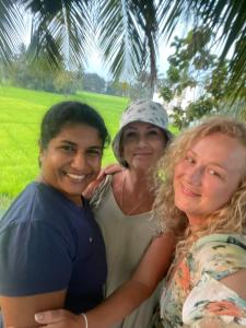 Tres mujeres posando para una foto bajo una palmera en Man Guest Polonnaruwa en Polonnaruwa