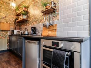 a kitchen with stainless steel appliances and white tiles at Emerald Cottage in Keighley