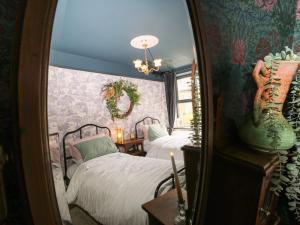 a bedroom with two beds and a mirror at Emerald Cottage in Keighley