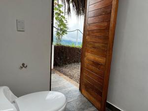 a bathroom with a toilet and a wooden door at Milagros Glamping in Agustín Codazzi