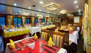un restaurante en un barco con mesas y sillas en Royal Palace Cruise en Ha Long