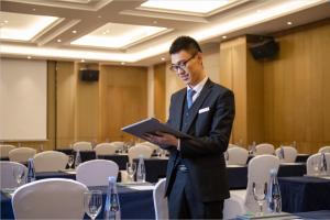 a man in a suit standing in a room with a tablet at Wanda Jin Pingxiang in Pingxiang