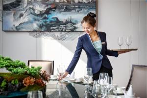Wanda Jin Pingxiang في Pingxiang: امرأة تقف على طاولة مع صينية من كؤوس النبيذ