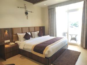 a bedroom with a large bed and a large window at Palm Resorts in Tinsukia