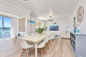 a dining room and living room with a table and chairs at New Property Silverwater Serenity Shores Absolute Waterfront On The Lake in Bonnells Bay