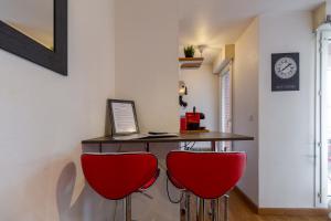 a bar with two red chairs and a table with a laptop at Studio ToulouseCityStay Basso Cambo in Toulouse