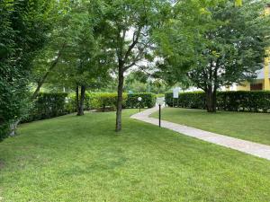 een park met groen gras en bomen en een stoep bij La Lanterna - Appartamento con Giardino in Residence con Piscina in Desenzano del Garda