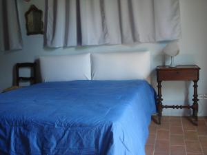 um quarto com uma cama azul, uma mesa de cabeceira e uma janela em La Vigna Apartment em Siena