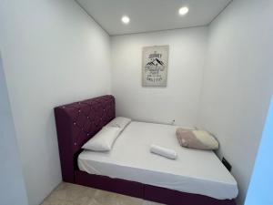 a small bedroom with a bed with a purple headboard at Vortex suites klcc by Hafizah suites in Kuala Lumpur