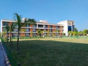 a hotel with a lawn in front of a building at Palm Resorts in Tinsukia
