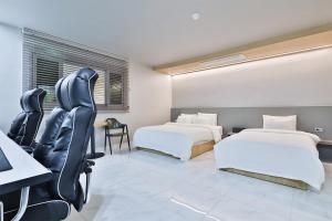 ein Hotelzimmer mit 2 Betten, einem Schreibtisch und Stühlen in der Unterkunft Shire Hotel Busan Station in Busan