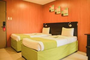 two beds in a room with orange walls at Jade Hotel and Suites in Manila