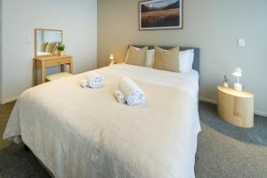 a bedroom with a large white bed with towels on it at In the heart of it all: 2 bed CBD townhouse in Christchurch
