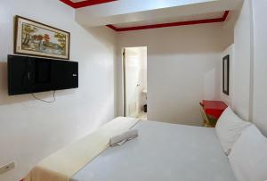 a bedroom with a bed and a tv on the wall at RedDoorz Hostel @ Tita Aidz Inn Baguio in Baguio