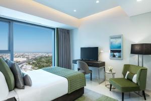 a hotel room with a bed and a desk and a window at DAMAC Maison Aykon City Dubai in Dubai