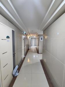 a long hallway with white walls and white tile floors at Gangnam Best Dormitory in Seoul
