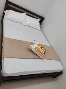 uma cama com lençóis brancos e uma almofada em Metropolis Staycation at Grass Residences em Manila