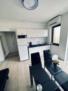 a kitchen with white cabinets and a table and chairs at Pinny Apartment in Portorož