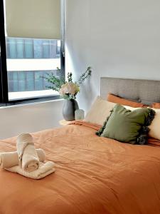 - un lit orange avec une serviette assise au-dessus dans l'établissement Minutes from Melbourne CBD - FREE Parking, à Footscray