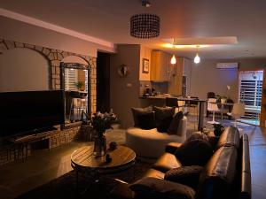 a living room with a couch and a tv and a table at L'Eden in Saint-Rémy-lès-Chevreuse