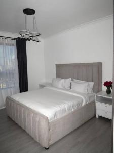 a white bedroom with a large bed and a lamp at Three Bedroom Luxury Apartment in Nairobi