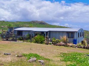 a blue building with a hill in the background at L'Arche in Rodrigues Island