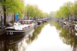 un barco está atracado en un canal en una ciudad en Prinsenboot, en Ámsterdam