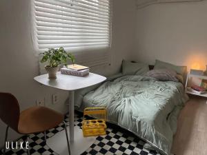 Un pequeño dormitorio con una cama y una mesa con una planta en Tolerance en Incheon