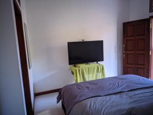Schlafzimmer mit einem TV an der Wand und einem Bett in der Unterkunft K'Ajeng Cottage in Penebel