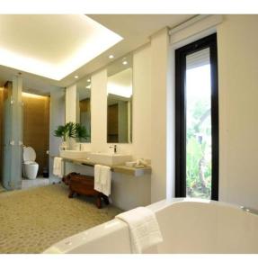 een badkamer met een bad, een wastafel en een spiegel bij Astoria Palawan in San Jose