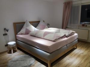 uma cama com lençóis brancos e almofadas num quarto em Ferienwohnung Bayerwaldblick em Jandelsbrunn