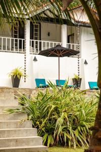 uma mesa com um guarda-chuva em frente a uma casa em Coco Tangalla em Tangalle