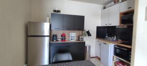a kitchen with a stainless steel refrigerator and black cabinets at Appart 4-6 pers au pied des pistes toutes saisons in Molines-en-Queyras +11 photos