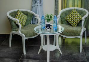 two chairs and a glass table in a room at La Grande Hotel in Kampala