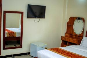a room with two beds and a mirror and a tv at La Grande Hotel in Kampala