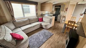 a living room with a couch and a kitchen at 8 BERTH Deluxe caravan PALM GROVE 142 GOLDEN PALM CHAPEL ST LEONARDS in Chapel Saint Leonards