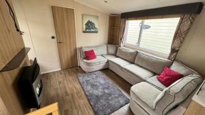 a living room with a couch and a tv at 8 BERTH Deluxe caravan PALM GROVE 142 GOLDEN PALM CHAPEL ST LEONARDS in Chapel Saint Leonards